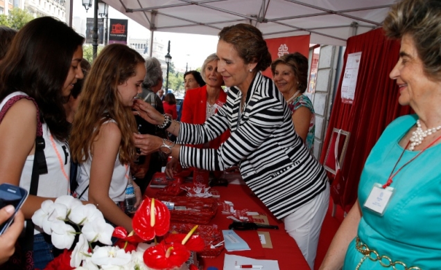 Doña Elena coloca la insignia de Cáritas a unas niñas que habían hecho su donativo